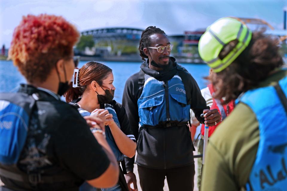 Escuela Verde School students T Anderson, 14, left, back to camera, Jadmary Flores, 15 and their science teacher Ediquelson Camara, right, wearing glasses, listen while water safety and canoe instructions are given at the  Wilderness Inquiry's Canoemobile at Lakeshore State Park on Monday, prior to going out on a canoe ride.