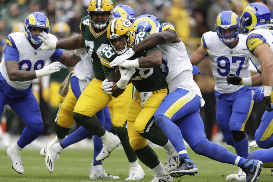 Green Bay Packers running back AJ Dillon (28) runs with the football as Los Angeles Rams linebacker Byron Young (0) attempts to tackle during the first half of an NFL football game Sunday, Nov. 5, 2023, in Green Bay, Wis. (AP Photo/Matt Ludtke)