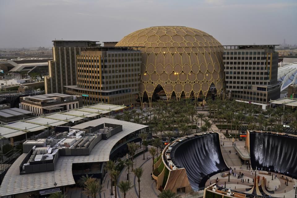 FILE - The Al Wasl Dome and the Water Feature glow at sunset at Expo 2020, in Dubai, United Arab Emirates, Oct. 3, 2021. Intent on making a flawless impression as the first host of the world’s fair in the Middle East, Dubai has spent over $7 billion on pristine fairgrounds and jubilant festivities. But propping up the elaborate fair is the United Arab Emirates’ contentious labor system that long has drawn accusations of mistreatment. (AP Photo/Jon Gambrell, File)