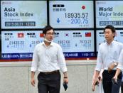 Japanese businessmen walk past a share prices board showing the numbers at the Tokyo Stock Exchange and other regional markets, in Tokyo on August 31, 2015