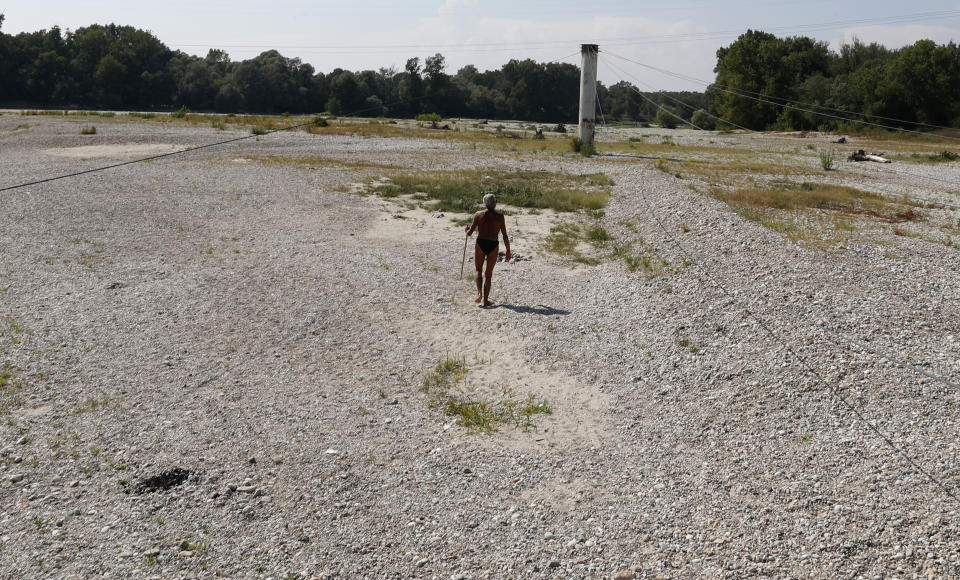 A man walks next to Ticino river in Bereguardo, near Pavia, Italy, Friday, Aug. 3, 2018. Hot air from Africa is bringing a heat wave to Europe, prompting health warnings about Sahara Desert dust and exceptionally high temperatures that could peak at 47 degrees Celsius (117 Fahrenheit). (AP Photo/Antonio Calanni)