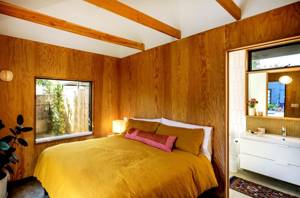 The bedroom, featuring a yellow duvet, and bathroom of the ADU.