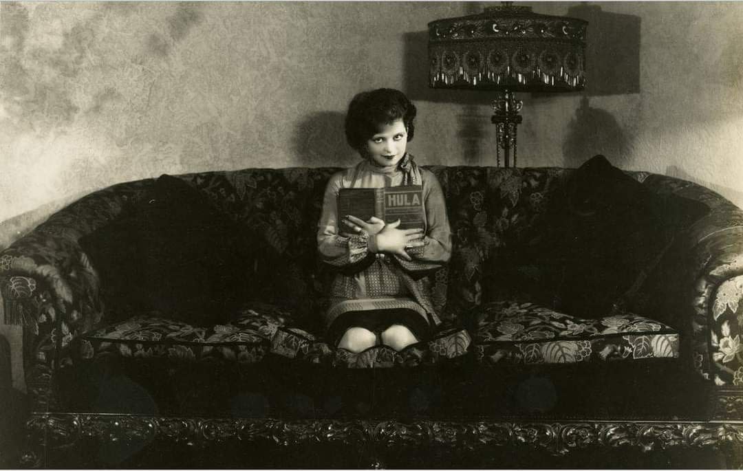 a child sitting on a couch reading a book