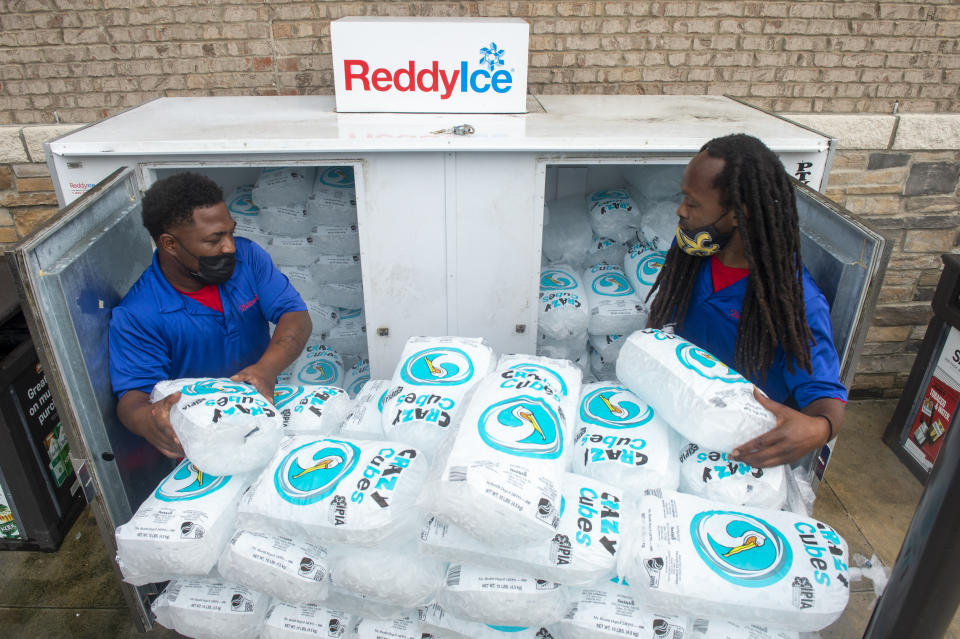 Corey Williams, right, and John Smith, both of Pelican Ice, hurriedly stack bags of ice into a gas station freezer in preparation for Tropical Storm Ida on Friday, Aug. 27, 2021 in Jefferson, La. Forecasters now say Ida could be a major Category 3 hurricane with top winds of 115 mph when it nears the U.S. coast. (Chris Granger/The Times-Picayune/The New Orleans Advocate via AP)