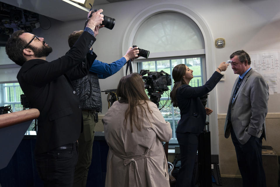 ADDS ID - Associated Press journalist Kevin Freking has his temperature checked before a coronavirus task force briefing, at the White House, Tuesday, March 17, 2020, in Washington. (AP Photo/Evan Vucci)