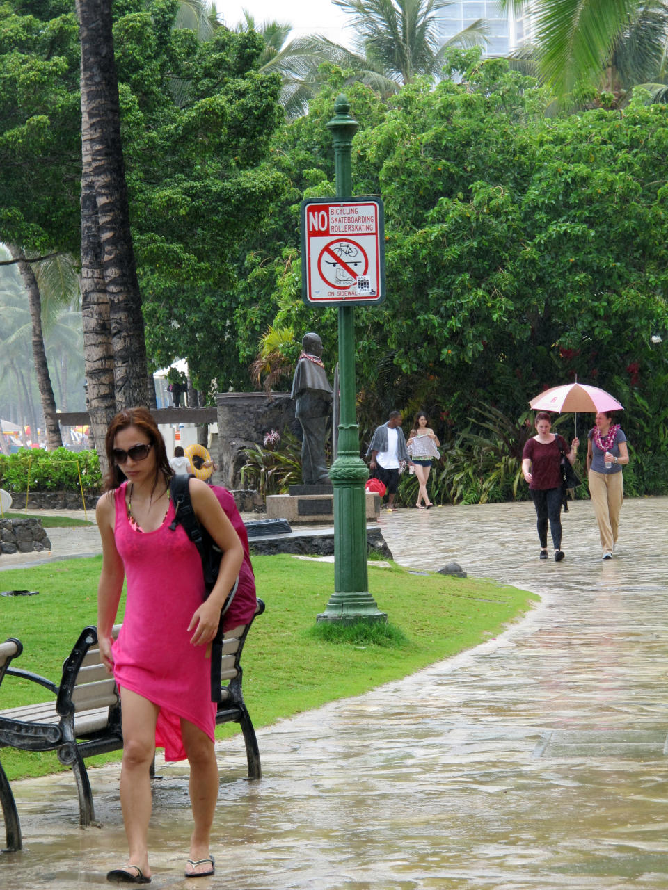 Pedestrians walk along Waikiki beach in Honolulu on Monday, July 29, 2013 as Tropical Storm Flossie approached Hawaii. The storm faded through the morning, but forecasters were still warning residents and tourists to brace for possible flooding, wind gusts, mudslides and big waves. (AP Photo/Audrey McAvoy)