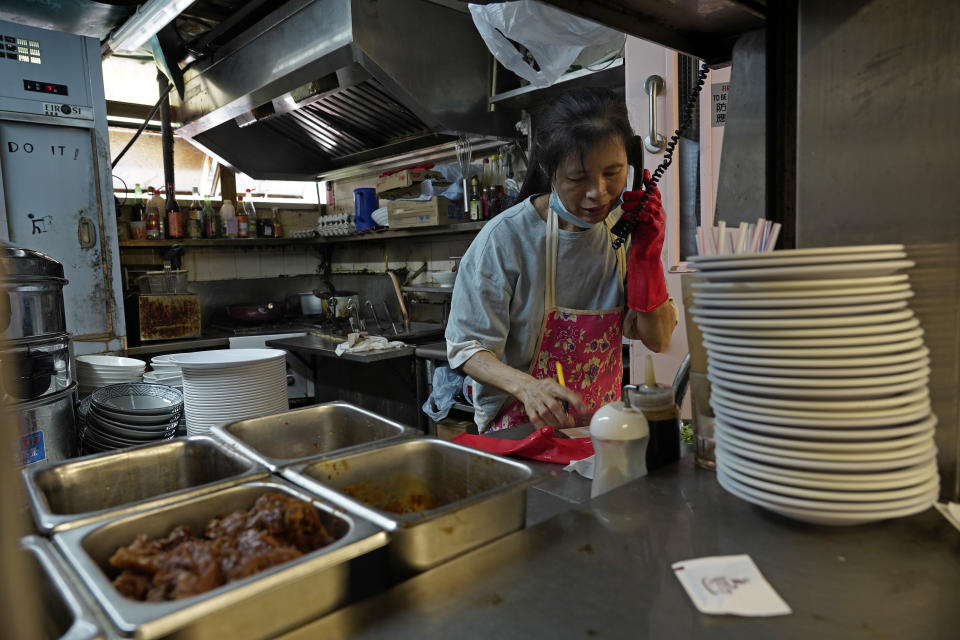 A restaurant employee takes phone orders at a Chinese food court in Hong Kong, Wednesday, July 29, 2020. Hong Kong has banned dining-in at restaurants completely on Wednesday and make it mandatory to wear masks in all public places, as the city battles its worst coronavirus outbreak to date. (AP Photo/Vincent Yu)