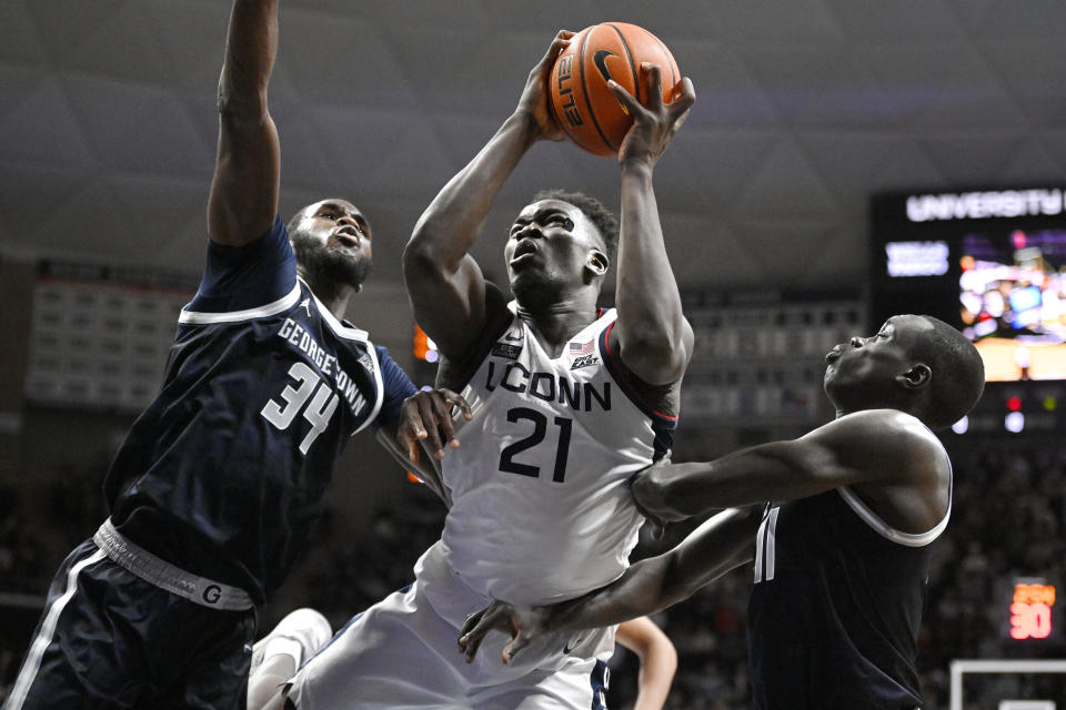 Connecticut's Adama Sanogo (21) shoots as Georgetown's Qudus Wahab (34) and Akok Akok (11) defend in the second half of an NCAA college basketball game, Tuesday, Dec. 20, 2022, in Storrs, Conn. (AP Photo/Jessica Hill)