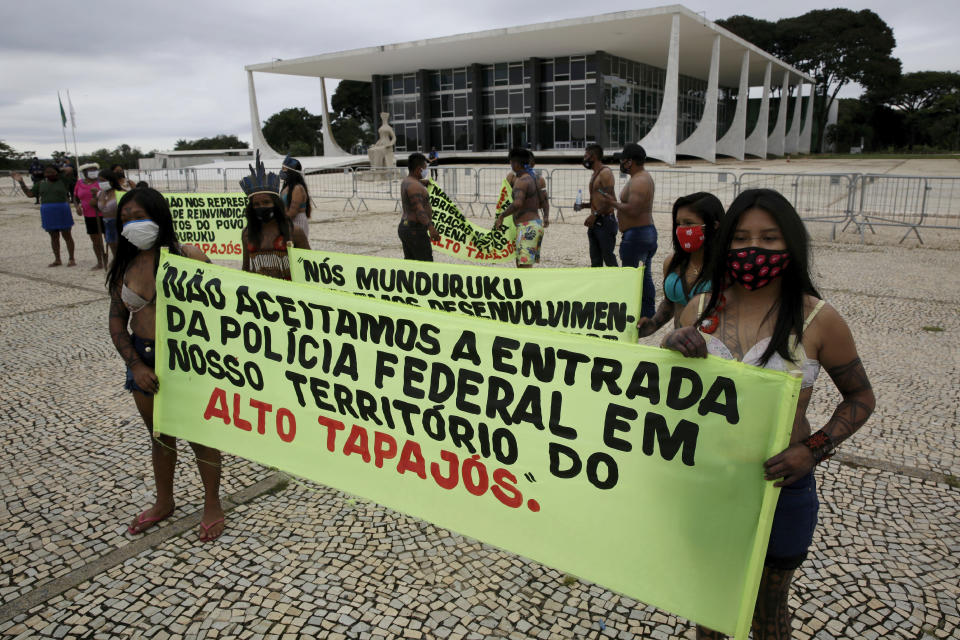 FILE - Munduruku Indigenous people from the Alto Tapajos in Para state hold the Portuguese sign "We do not accept entry of the Federal Police on our Alto Tapajos territory," referring the expelling of miners by the Federal Police from Indigenous lands in Para state, outside the Supreme Court to show support for Brazilian President Jair Bolsonaro's proposals to allow mining on Indigenous lands in Brasilia, Brazil, April 19, 2021. Some Indigenous leaders see gold mining as a potential economic boon for the area that could bring jobs and investments, while others see it as defiling the land. (AP Photo/Eraldo Peres, File)