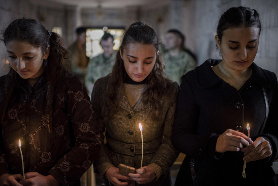 Iraqis attend Christmas Eve's Mass in the Assyrian Orthodox church of Mart Shmoni, in Bartella, Iraq, Saturday, December 24, 2016. For the 300 Christians who braved rain and wind to attend the mass in their hometown, the ceremony provided them with as much holiday cheer as grim reminders of the war still raging on around their northern Iraqi town and the distant prospect of moving back home. Displaced when the Islamic State seized their town in 2014, they were bused into the town from Irbil, capital of the self-ruled Kurdish region, where they have lived for more than two years. (AP Photo/Cengiz Yar)