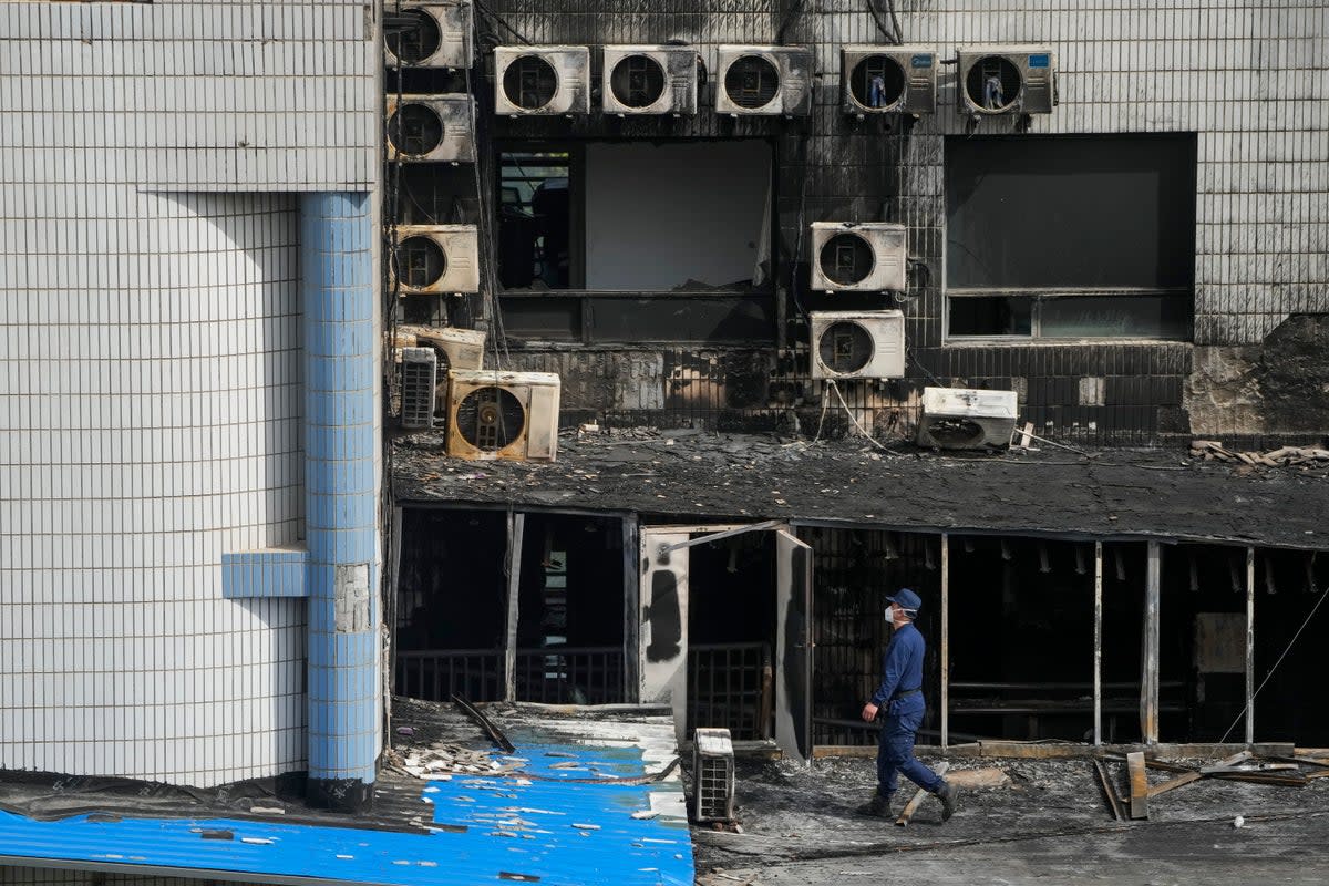 An investigator inspects burnt out area following a fire at a hospital in Beijing (AP)