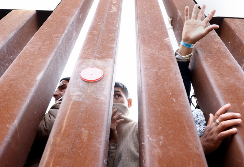 Immigrants stuck in a makeshift camp between the U.S. and Mexico look through the border wall as volunteers offer assistance on the other side on May 13, 2023 in San Diego, California.<span class="copyright">Mario Tama—Getty Images</span>