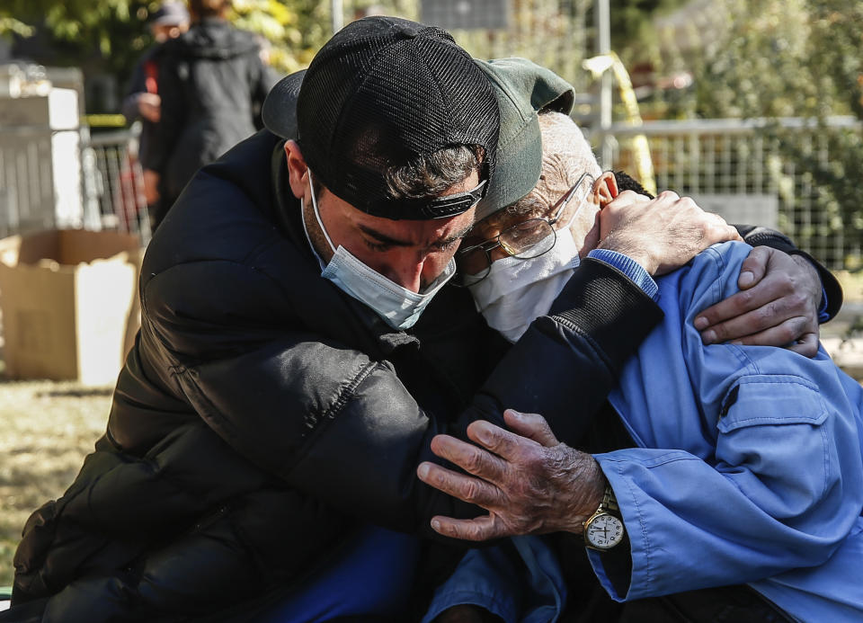 Local residents comfort each other as they watch members of rescue services working on the search for survivors in the debris of a collapsed building, in Izmir, Turkey, Monday, Nov. 2, 2020. Rescue teams continue ploughing through concrete blocs and debris of collapsed buildings in Turkey's third largest city in search of survivors of a powerful earthquake that struck Turkey's Aegean coast and north of the Greek island of Samos, Friday Oct. 30, killing dozens. Close to a thousand people were injured.(AP Photo/Emrah Gurel)