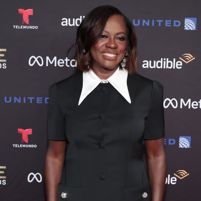 Viola Davis in a black dress with a white collar and button details, posing at an event