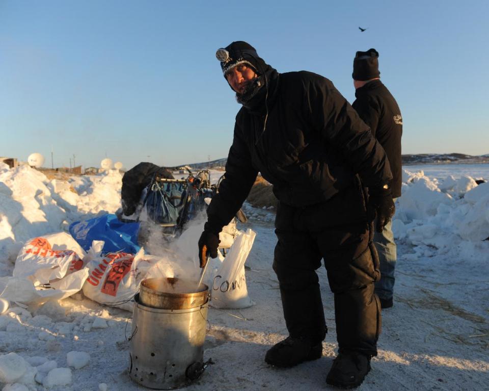 Iditarod musher John Baker, from Kotzebue, Ak, prepares dog food for his team at the Unalakleet checkpoint at sunrise during the 2014 Iditarod Trail Sled Dog Race on Sunday, March 9, 2014. (AP Photo/The Anchorage Daily News, Bob Hallinen)