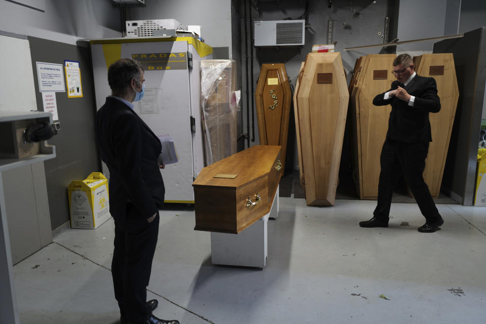 Paris undertaker Franck Vasseur, left and pallbearer, Allan Pottier, right, prepare a coffin at a mortuary, in Paris, Friday, April 24, 2020 as a nationwide confinement continues to counter the COVID-19 virus. (AP Photo/Francois Mori)