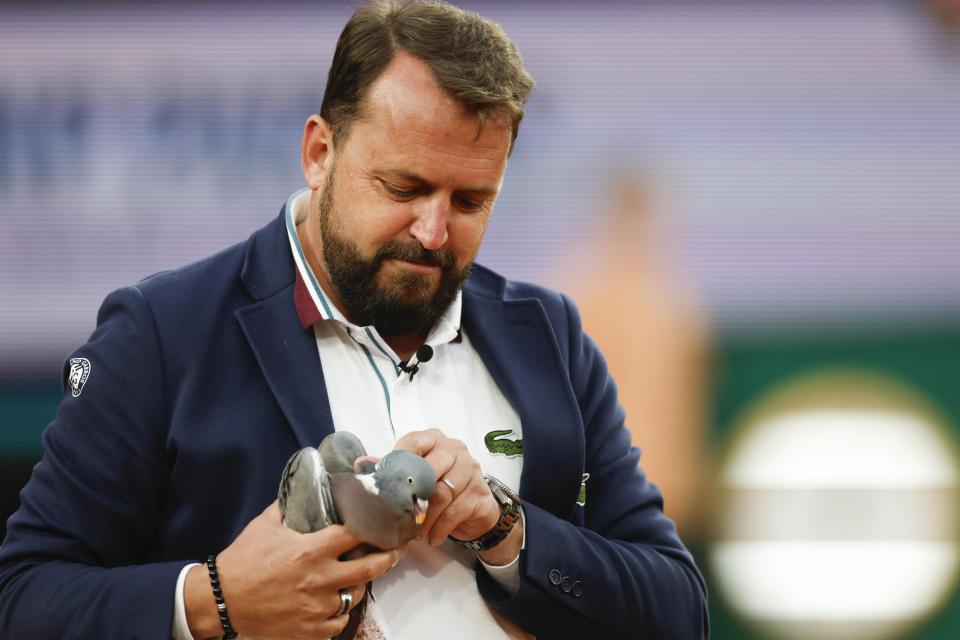 El juez de silla Damien Dumusois atrapa una paloma que acabó en la pista durante el partido entre Tomas Machac y Daniil Medvedev en la tercera ronda del Abierto de Francia, el sábado 1 de junio de 2024. (AP Foto/Jean-Francois Badias)