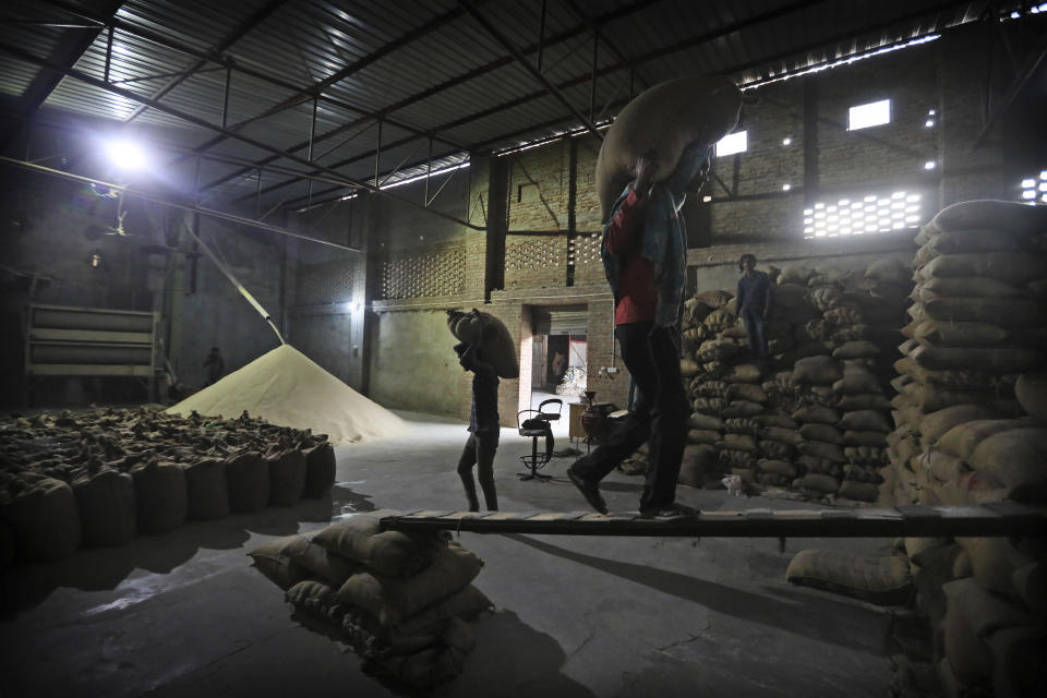 Laborers stack rice in a private warehouse in Makhu, in the Indian state of Punjab, Friday, March 12, 2021. India's water crisis looms over the agrarian crisis that has been brewing for decades. And at its heart is a policy conundrum: India has been subsidizing the cultivation of rice in northern India, but these are thirsty crops that have depleted the ground water. (AP Photo/Manish Swarup)