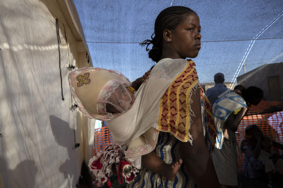 A Tigray refugee mother carries her child as she waits her turn for treatment at a clinic run by MSF (Doctors Without Borders) in Village 8, the transit centre near the Lugdi border crossing, eastern Sudan, Tuesday, Dec. 8, 2020. (AP Photo/Nariman El-Mofty)