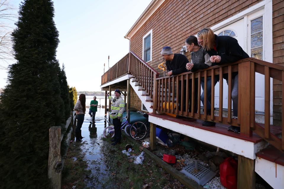 East Bridgewater Fire Chief Timothy Harhen, center, speaks with residents whose homes were flooded along Bixby Drive, which borders Robbins Pond, on Friday, Jan. 27, 2023.