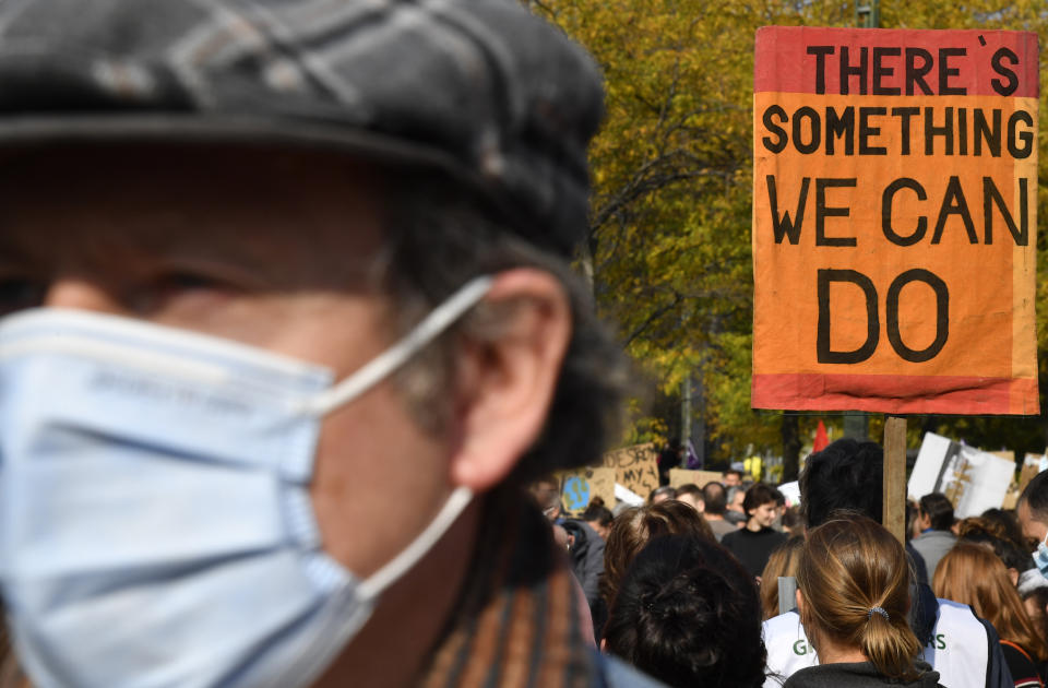 A woman carries a sign as she participates in a climate march in Brussels, Sunday, Oct. 10, 2021. Some 80 organizations are joining in a climate march through Brussels to demand change and push politicians to effective action in Glasgow later this month.(AP Photo/Geert Vanden Wijngaert)