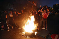 Anti-government protesters chant slogans as they burn barriers to block a road during a protest against the political leadership they blame for the economic and financial crisis, in front of the government house in downtown Beirut, Lebanon, Thursday, June 11, 2020. (AP Photo / Hussein Malla)