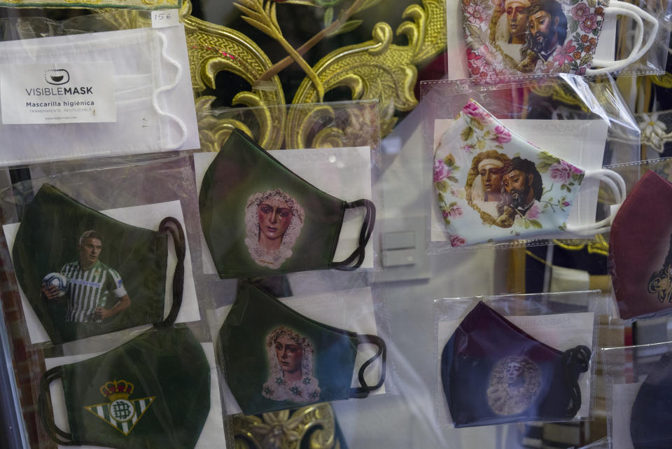 Face masks with images of Jesus, Virgin Mary and soccer players are displayed in a shop during the Holy Week in Seville, southern Spain, Tuesday, March 30, 2021. Few Catholics in devout southern Spain would have imagined an April without the pomp and ceremony of Holy Week processions. With the coronavirus pandemic unremitting, they will miss them for a second year. (AP Photo/Laura Leon)