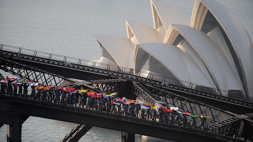 People holding up flags from all over the world on the 10th anniversary of the BridgeClimb. Source: Getty Images