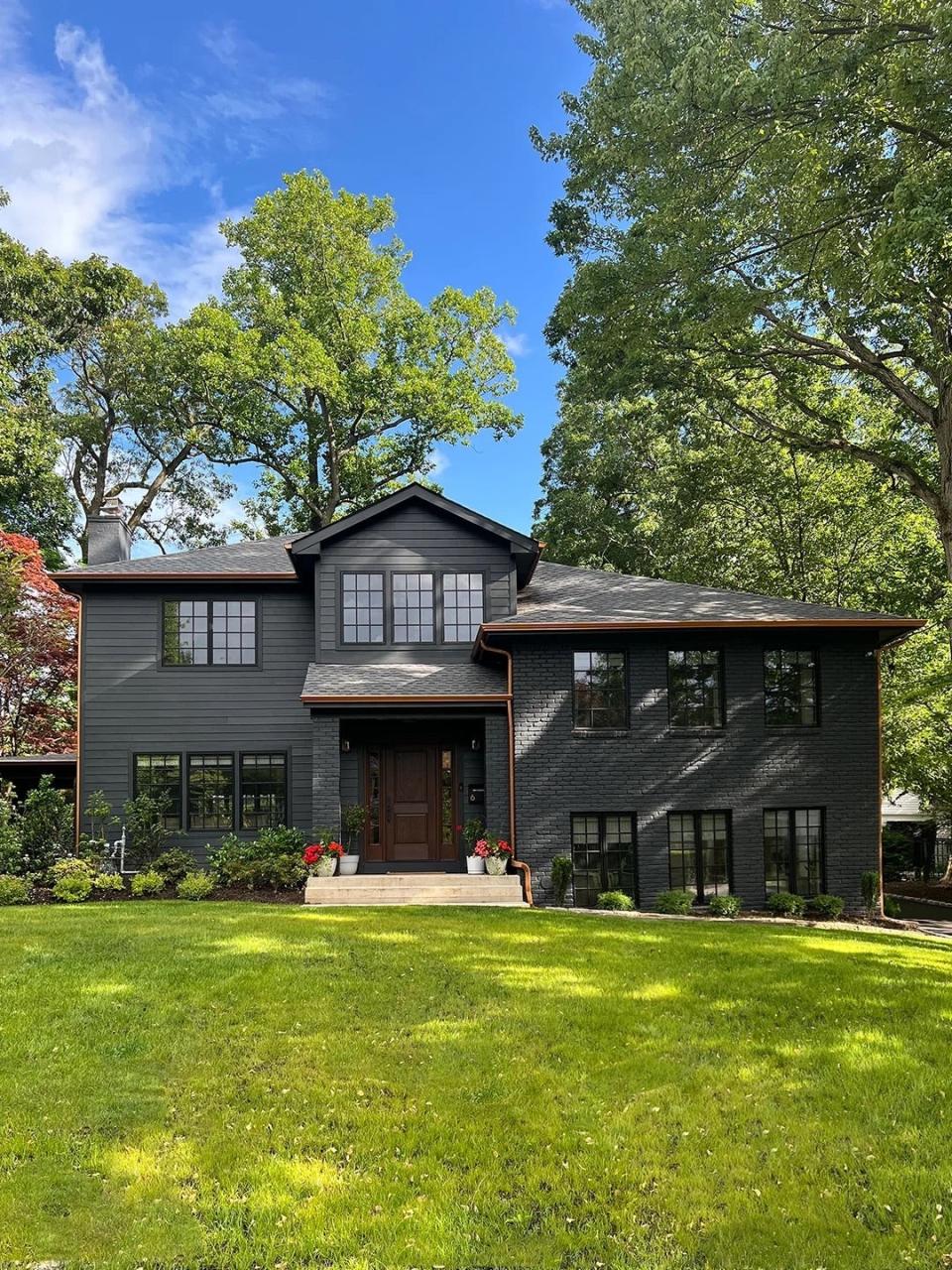 Brick home painted black with nature surroundings.