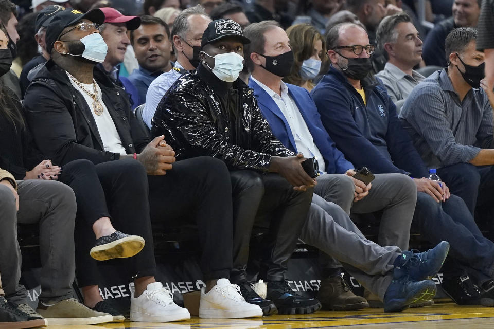 San Francisco 49ers NFL football player Deebo Samuel, center left, looks on during the first half of an NBA basketball game between the Golden State Warriors and the Memphis Grizzlies next to Warriors owner Joe Lacob, center right, in San Francisco, Thursday, Oct. 28, 2021. (AP Photo/Jeff Chiu)