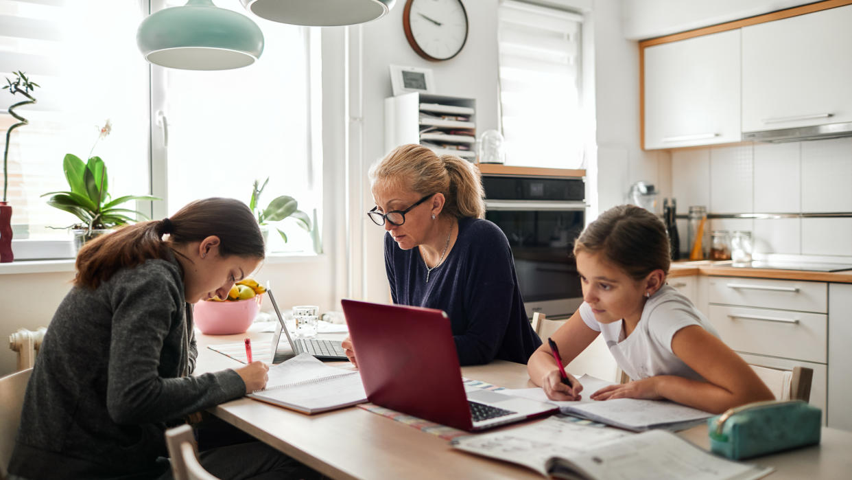 Mother helping her daughters to finish school homework during coronavirus quarantine.