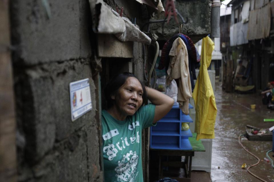 Luzviminda Limas goes out of their house after floods recede in suburban Marikina city, east of Manila, Philippines on Friday Aug. 10, 2012. The 54-year-old widow said the floods this week brought back memories of the 2009 deluge when she was huddled under an umbrella with one of her two daughters and her four-month old grandson on the roof of a day-care center beside her house as floodwaters rampaged through her neighborhood during a typhoon. The flood then destroyed her home. (AP Photo/Aaron Favila)