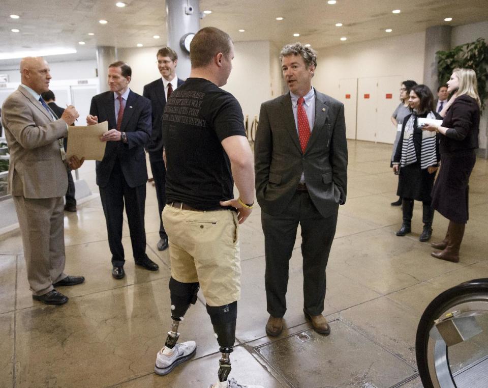 Sen. Rand Paul, R-Ky., a member of the Senate Foreign Relations Committee, center, stops to speak to a wounded military veteran as he and other lawmakers make their way to the chamber to advance a bill providing $1 billion in loan guarantees to Ukraine as President Barack Obama meets with U.S. allies in Europe to punish Moscow for its annexation of the Crimean peninsula, at the Capitol in Washington, Monday, March 24, 2014. (AP Photo/J. Scott Applewhite)