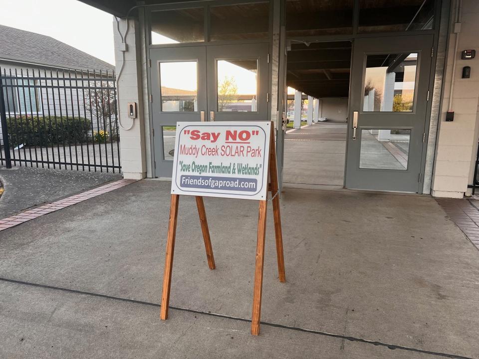 A sign saying "Say No Muddy Creek Solar Park Save Oregon Farms and Wetlands" stands outside of Harrisburg High School during a town hall event hosted in March.