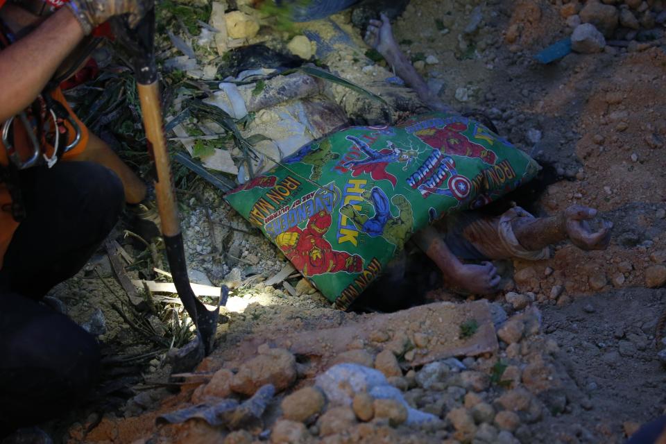 Rescuers reveal a father and his daughter in an embrace following a landslide that buried dozens of homes in Naga city, Cebu province central Philippines on Thursday Sept. 20, 2018. A landslide set off by heavy rains buried homes under part of a mountainside in the central Philippines on Thursday, and several people are feared buried, including two who sent text messages seeking help. (AP Photo/Bullit Marquez)