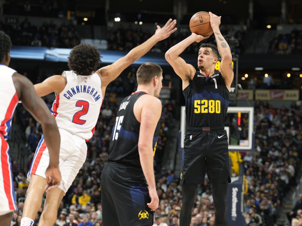 Detroit Pistons guard Cade Cunningham (2) reaches over a pick set by Denver Nuggets center Nikola Jokic (15) to foul forward Michael Porter Jr., right, who takes a 3-point shot in the first half of an NBA basketball game Sunday, Jan. 7, 2024, in Denver. (AP Photo/David Zalubowski)