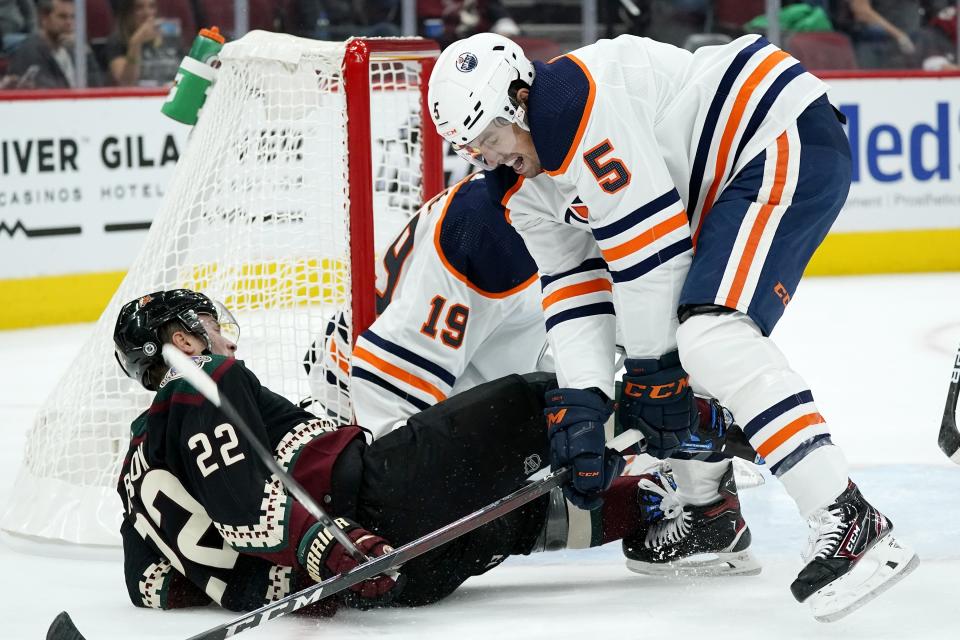 Edmonton Oilers defenseman Cody Ceci (5) knocks Arizona Coyotes left wing Johan Larsson (22) off the puck and to the ice during the first period of an NHL hockey game Thursday, Oct. 21, 2021, in Glendale, Ariz. (AP Photo/Ross D. Franklin)