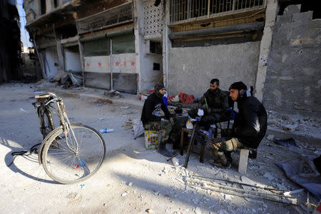 Forces loyal to Syria's President Bashar al-Assad sit in front of damaged shops in a government held area of Aleppo, Syria December 9, 2016. REUTERS/Omar Sanadiki