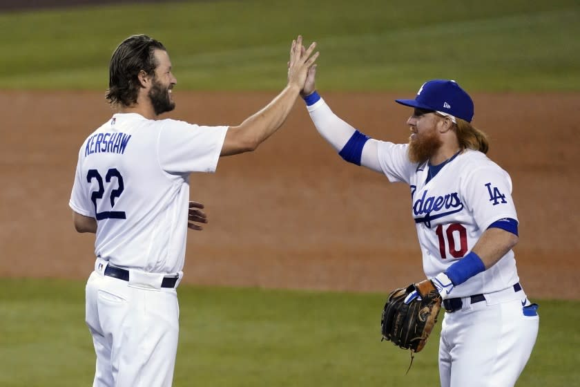 Los Angeles Dodgers starting pitcher Clayton Kershaw, left, high-fives Justin Turner.