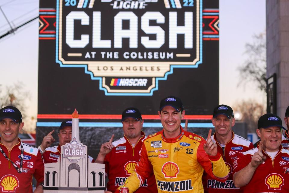 El piloto de NASCAR Joey Logano se toma fotos con su tripulación y el trofeo después de ganar el Busch Light Clash en el Coliseo.