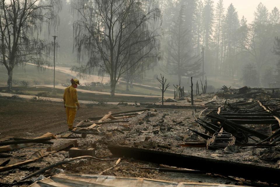 A firefighter searches for human remains in a trailer park destroyed in the Camp Fire in Paradise (AP)