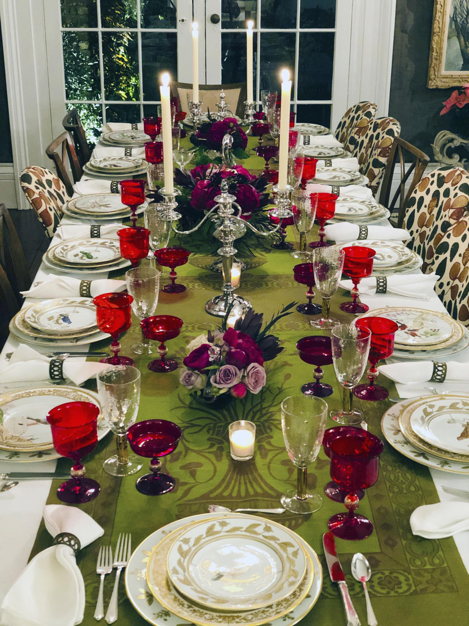 This photo provided by interior designer Elizabeth Stuart shows a table setting design by Stuart in a residence in Charleston, S.C. When setting a beautiful holiday table, consider using several small, low centerpieces rather than one large one, as seen on this table designed by the South Carolina-based interior designer. It helps to ensure that your table decoration isn’t blocking one guest’s view of another. (Elizabeth Stuart via AP)