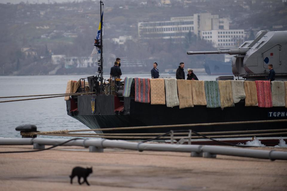 People work on board the Ukrainian navy corvette Ternopil, background, at harbor of in Sevastopol, Ukraine, Tuesday, March 4, 2014. Crimea still remained a potential flashpoint. Pro-Russian troops who had taken control of the Belbek air base in Crimea fired warning shots into the air Tuesday as around 300 Ukrainian soldiers, who previously manned the airfield, demanded their jobs back. The blankets and mattresses are placed over the side of the ship to hinder any attempted assault. (AP Photo/Andrew Lubimov)