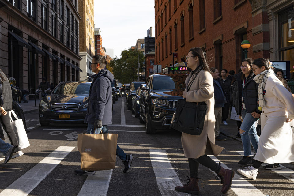 FILE - Shoppers holding bags cross Prince Street on Black Friday in New York, Friday, Nov. 24, 2023. If you’re planning on grabbing groceries or doing some other shopping this New Year’s Day, it’s wise to double check stores’ hours.(AP Photo/Peter K. Afriyie, File)