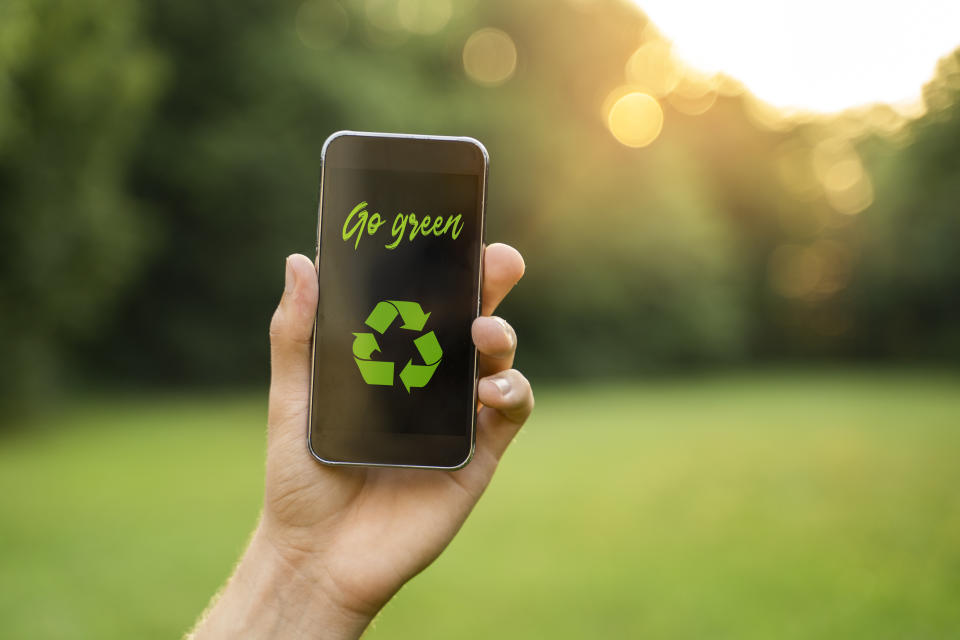 Go green concept, man in nature holding smartphone with go green text and recycle symbol