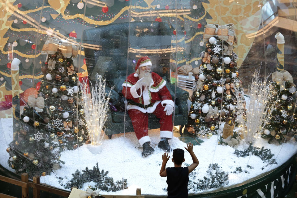 Abilio Nunes, a Santa Claus performer, waves to children from inside a bubble, a protective measure against the spread of COVID-19, at a shopping center in Brasilia, Brazil, Wednesday, Dec. 16, 2020. (AP Photo/Eraldo Peres)