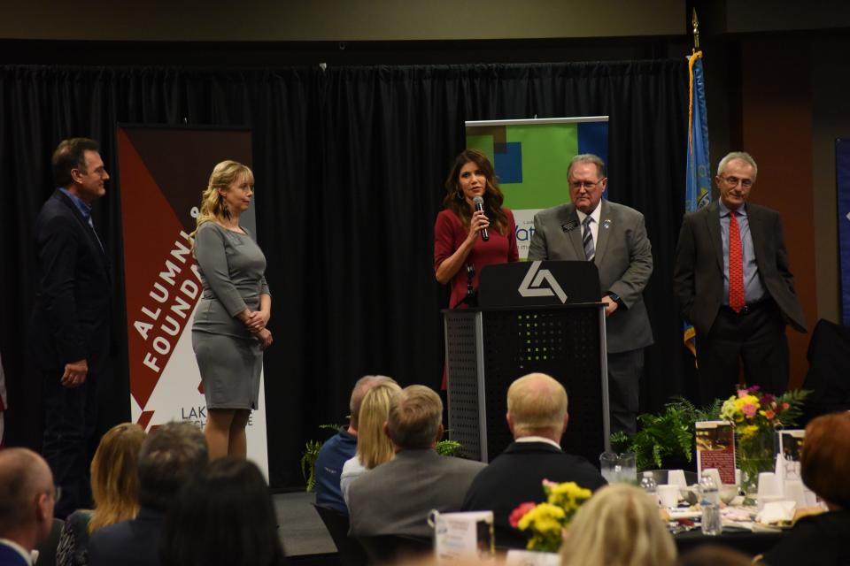 Gov. Kristi Noem (center) speaks at the Governor's Annual Luncheon at Lake Area Technical College in Watertown on May 6, 2022. Lt. Gov. Larry Rhoden (far left), Sen. Jessica Castleberry (left), Sen. Hugh Bartels (right) and Sen. Lee Schoenbeck (far right) stand onstage as Noem speaks.