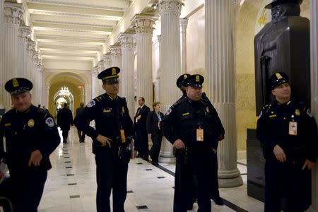 U.S. Capitol Police officers stand just outside the House chamber as they watch a telecast of U.S. President Barack Obama delivering his final State of the Union address to a joint session of Congress in Washington January 12, 2016. REUTERS/James Lawler Duggan