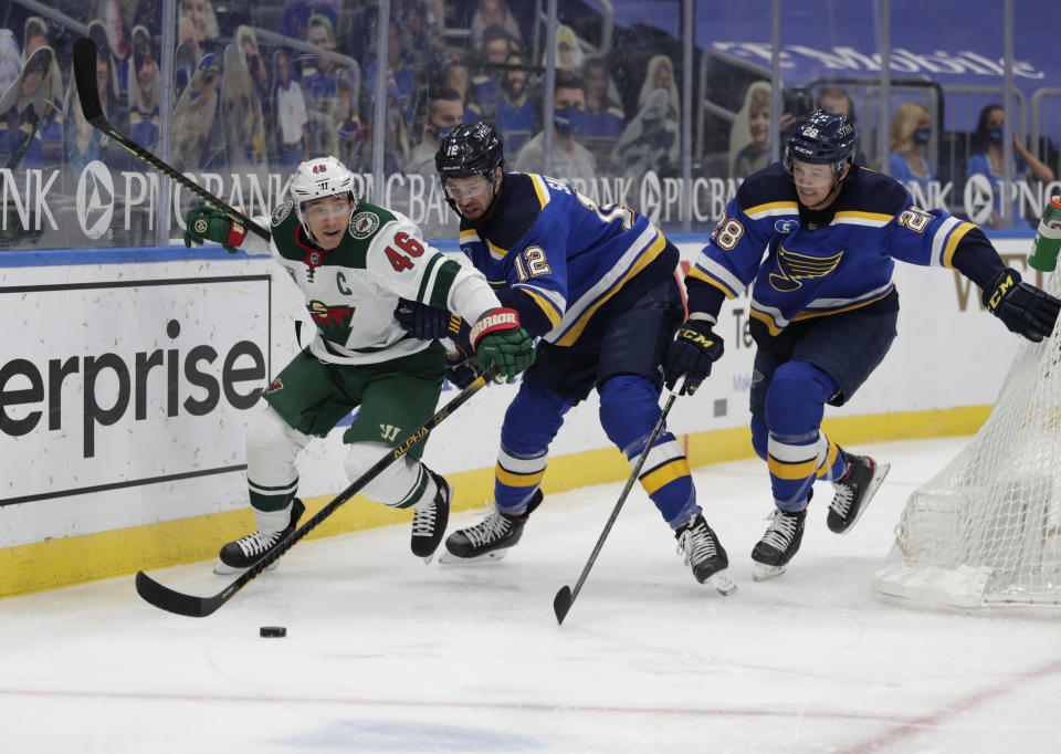 Minnesota Wild's Jared Spurgeon (46) battles St. Louis Blues' Zach Sanford (12) and Mackenzie MacEachern (28) for the loose puck in the second period of an NHL hockey game, Wednesday, May 12, 2021 in St. Louis. (AP Photo/Tom Gannam)