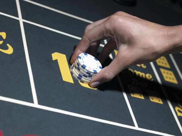 Hand placing gambling chips on a casino table.